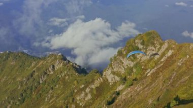 Aerial view a paraglider flies over a mountain ridge
