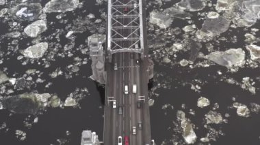 ice floes float on the river under the bridge. cars go over the bridge