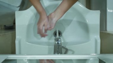 Kadın ellerini lavabonun üstüne koyar..