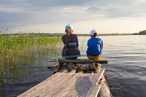 Мальчик и девочка, сидящие на берегу — стоковое фото
