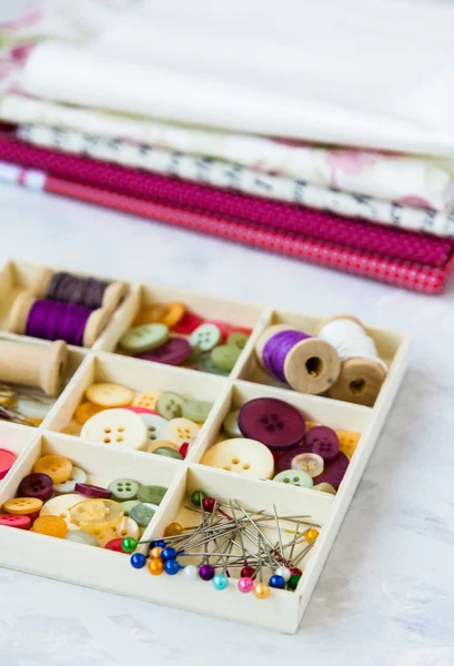needles, thread, pins, buttons are in a box