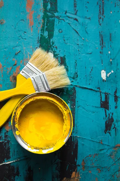 A jar of yellow paint stands on a blue background
