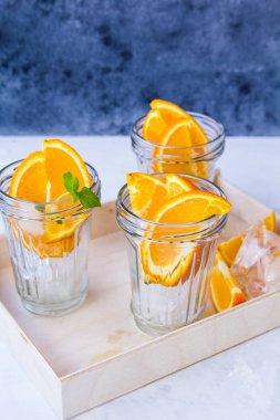 Buz ve portakal dilimleri ile gözlük bir ahşap tepsi üzerinde durmak