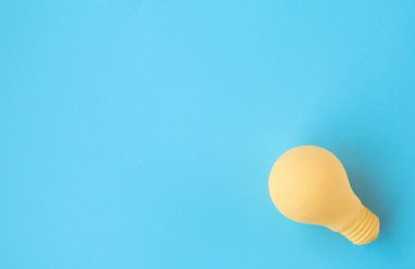 Sarı bir ampul mavi bir arka plan üzerinde yatıyor