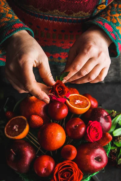 woman makes a bouquet of fruit and flowers