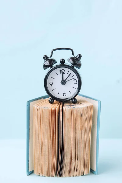 Black Alarm Clock Blue Background Book — Stock Photo, Image