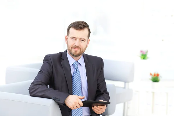 Boldog üzletember ül a kanapén, látszó-on fényképezőgép az irodában — Stock Fotó