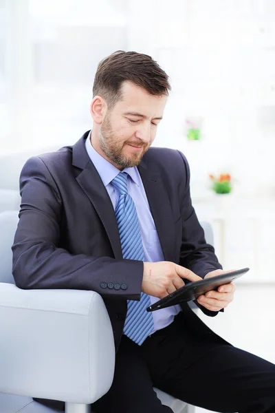 Happy businessman sitting on the sofa looking at camera in the office — Stock Photo, Image