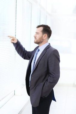 genç ve yakışıklı bir işadamı güneşlikler ile pencereden dışarı bakıyor