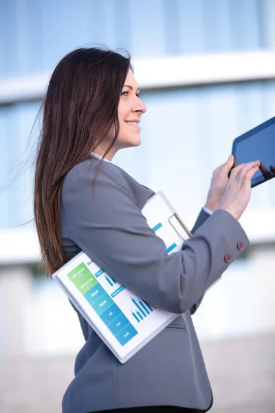 Businesswoman working on digital tablet outdoor over building background — Stock Photo, Image