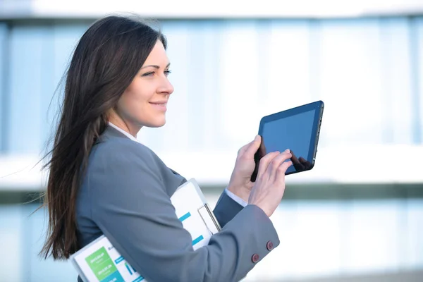 Mujer de negocios que trabaja en tableta digital al aire libre sobre el fondo del edificio —  Fotos de Stock