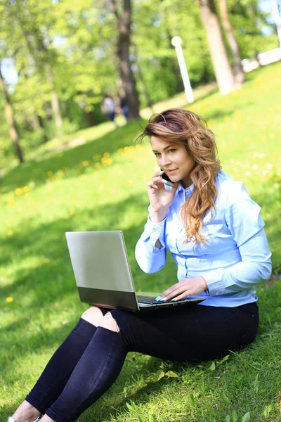 Giovane bella donna si trova sul prato verde estivo con computer portatile — Foto Stock