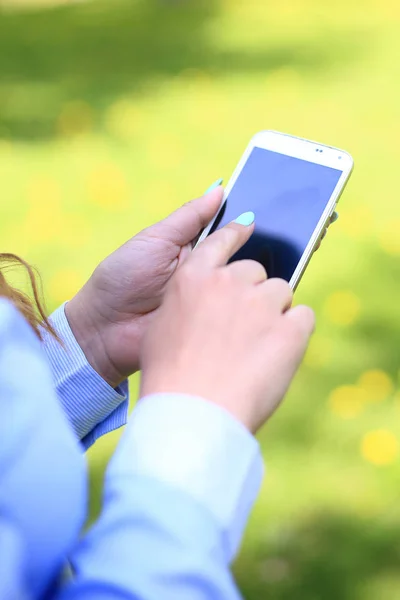 Žena pomocí mobilního telefonu v parku. — Stock fotografie