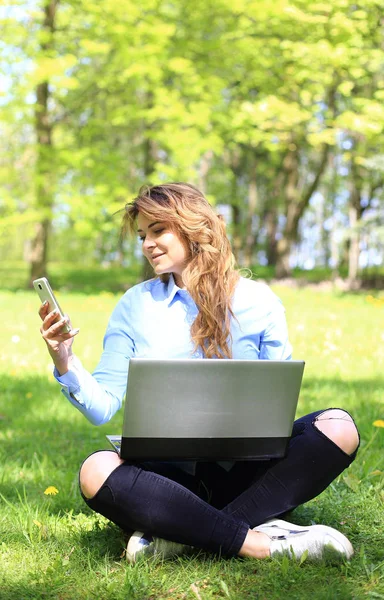 Young pretty girl working on laptop outdoor, lying on grass, caucasian 20 years old — Stock Photo, Image