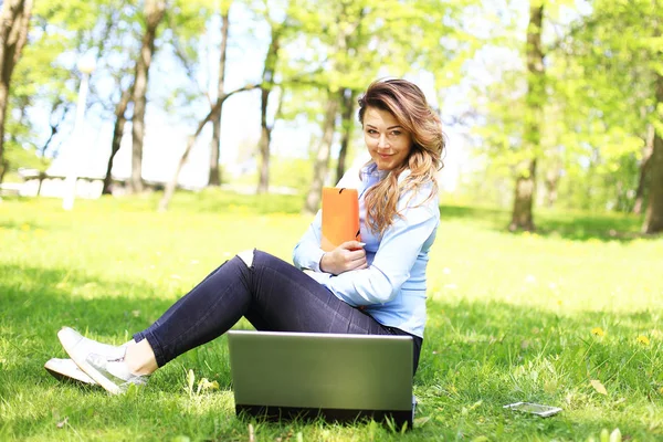 Young pretty girl working on laptop outdoor, lying on grass, caucasian 20 years old — Stock Photo, Image