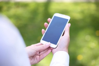 Parkta mobil akıllı telefon kullanan kadın.