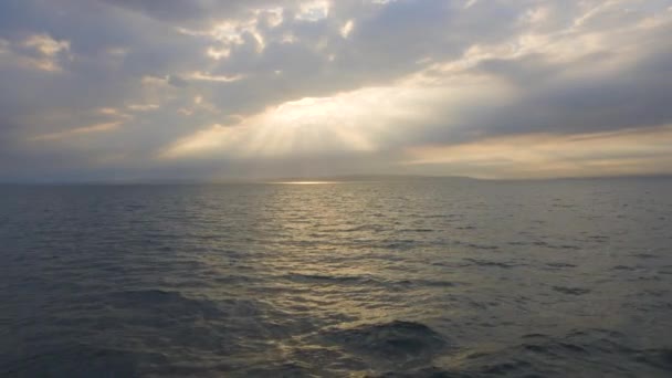 Krásné paprsky slunce spadnout na hladinu moře přes mraky. Pohled z plovoucí jachty — Stock video