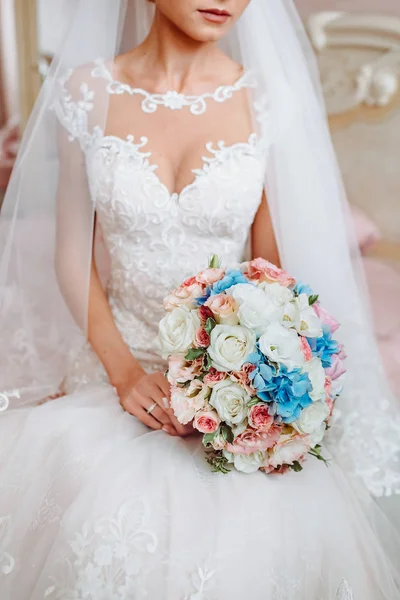 Mariée en robe sur le lit tenant bouquet de mariage — Photo