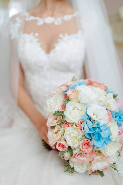 Невеста в платье на кровати с свадебным букетом
