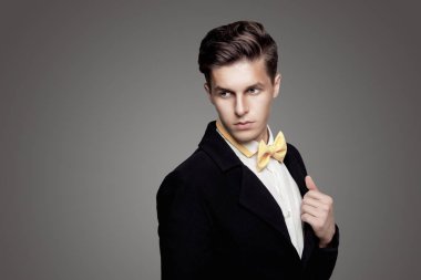 Trendy delikanlı. Siyah Süiti, sarı papyon, gri arka plan. Portre