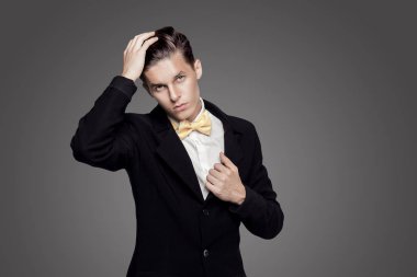 Trendy delikanlı. Siyah Süiti, sarı papyon, gri arka plan. Portre