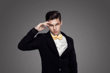Trendy delikanlı. Siyah Süiti, sarı papyon, gri arka plan. Portre