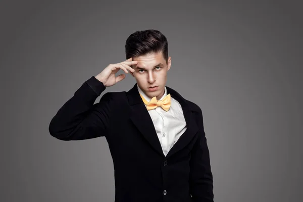 Junger trendiger Mann. schwarze Suite, gelbe Fliege, grauer Hintergrund. Porträt — Stockfoto