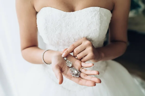 Elegantní nevěstu hospodářství stříbrné náušnice. Nabídková ruce s šperky. — Stock fotografie