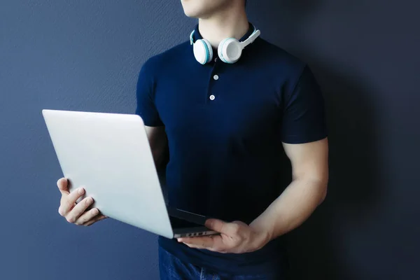 Молодий атлетичний чоловік у футболці з навушниками та ноутбуком . — стокове фото