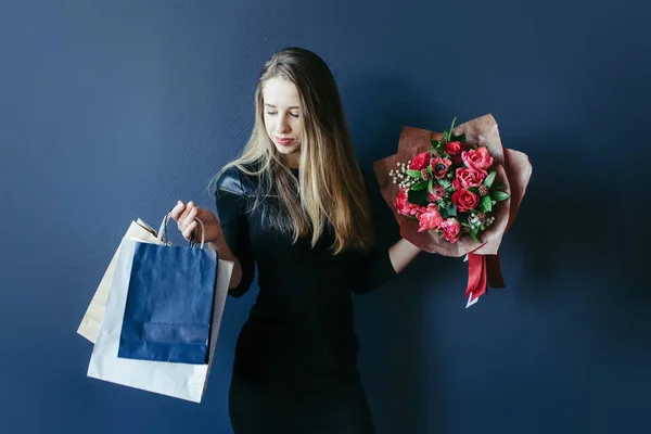 Schattig meisje met bouquet van rode tulpen en pakketten. — Stockfoto