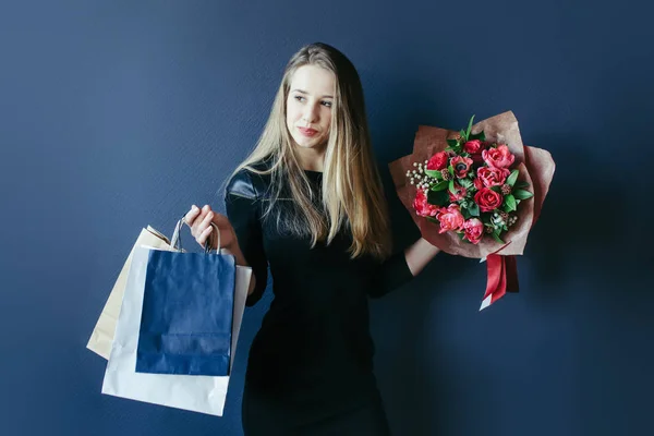 Schattig meisje met bouquet van rode tulpen en pakketten. — Stockfoto