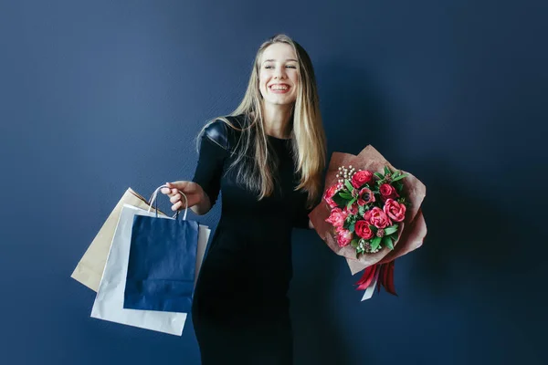 Schattig meisje met bouquet van rode tulpen en pakketten. — Stockfoto