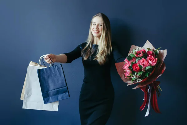 Schattig meisje met bouquet van rode tulpen en pakketten. — Stockfoto