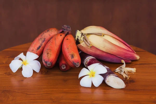新鲜香蕉束未熟的香蕉和花，木桌 — 图库照片