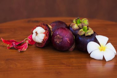 Çiçek ve yaprak üzerinde ahşap kahverengi masa ile taze mangosteens