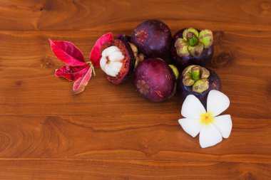 Çiçek ve yaprak üzerinde ahşap kahverengi masa ile taze mangosteens