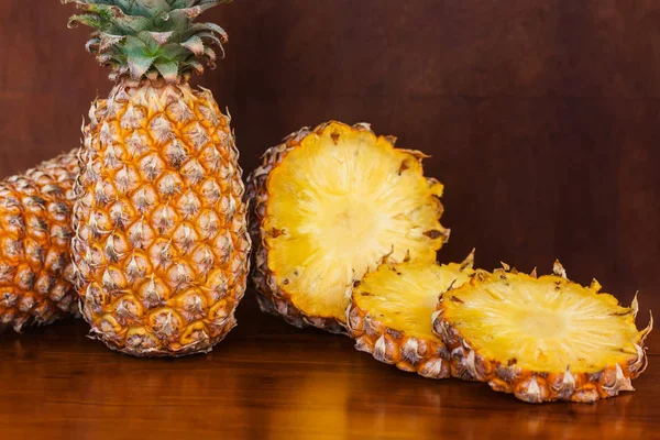 Two whole and some cutting slices pineapples on wooden table — Stock Photo, Image