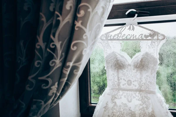 Vestido de noiva pendurado em uma janela — Fotografia de Stock