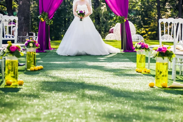 Braut steht im Hochzeitsbogen mit Stühlen auf jeder Seite — Stockfoto