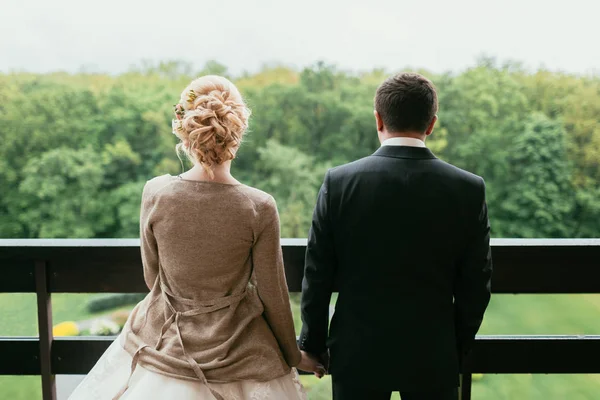 Nevěsta a ženich stojí za plotem přední park — Stock fotografie