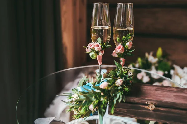 Two champagne glasses decorated with small boutonniere — Stock Photo, Image