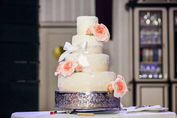 Bröllopstårta dekorerad med rosor, spets och rosett — Stockfoto