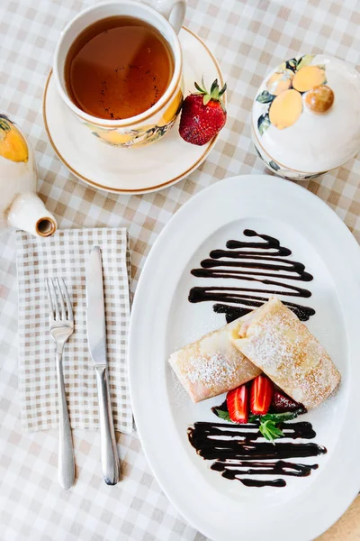 Pancakes with chocolate, strawberry and mint, with cup of tee — Stock Photo, Image