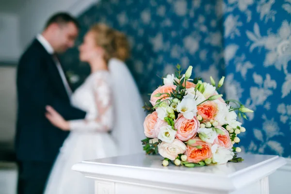 Bröllop bukett på bakgrunden av kramar bruden och brudgummen — Stockfoto