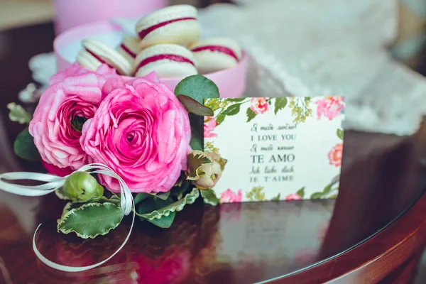 Růže a francouzské makronky dort. Barevné makronky v krabici s květy vedle na dřevěný stůl. — Stock fotografie
