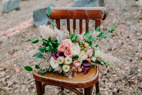 Krásné svatební kytice na staré hnědé křeslo stojí venku. — Stock fotografie