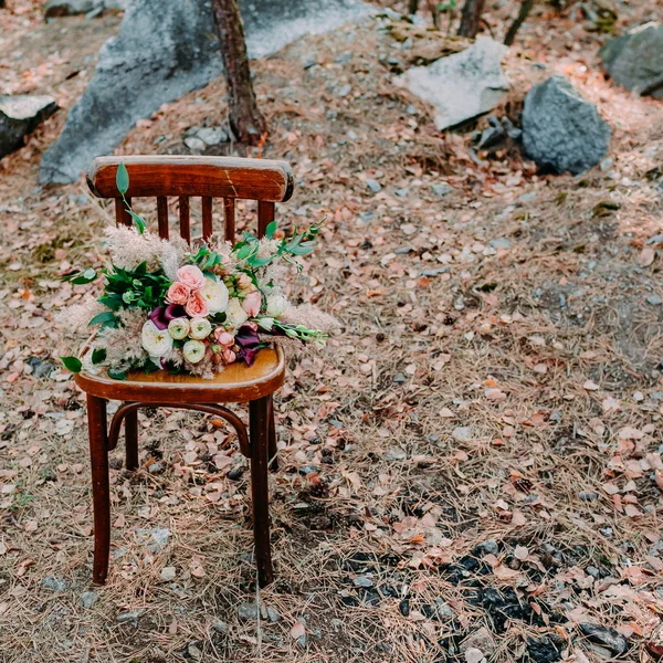 Piękny ślub bukiet na stary fotel brązowy, stojący na zewnątrz w parku. — Zdjęcie stockowe