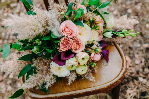 Beautiful wedding bouquet on an old brown chair standing outside in park. — Stock Photo, Image