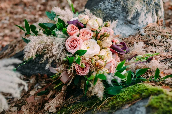 美丽的婚礼花束组成的不同花躺在公园的石头上。秋季婚礼 — 图库照片