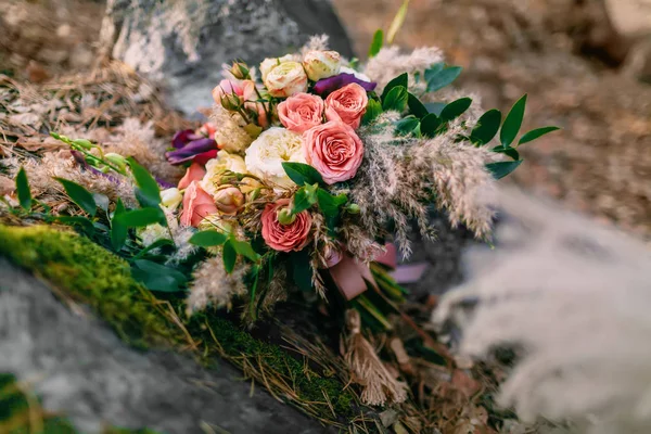 Beautiful wedding bouquet consisting of different flowers lying on a stone in the park. Autumn wedding — Stock Photo, Image